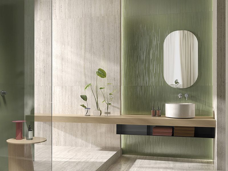 Badezimmer mit Fliesen in heller Travertinoptik, grüner Rillen-Wandfliese und Holzablage mit Aufsatzbecken
