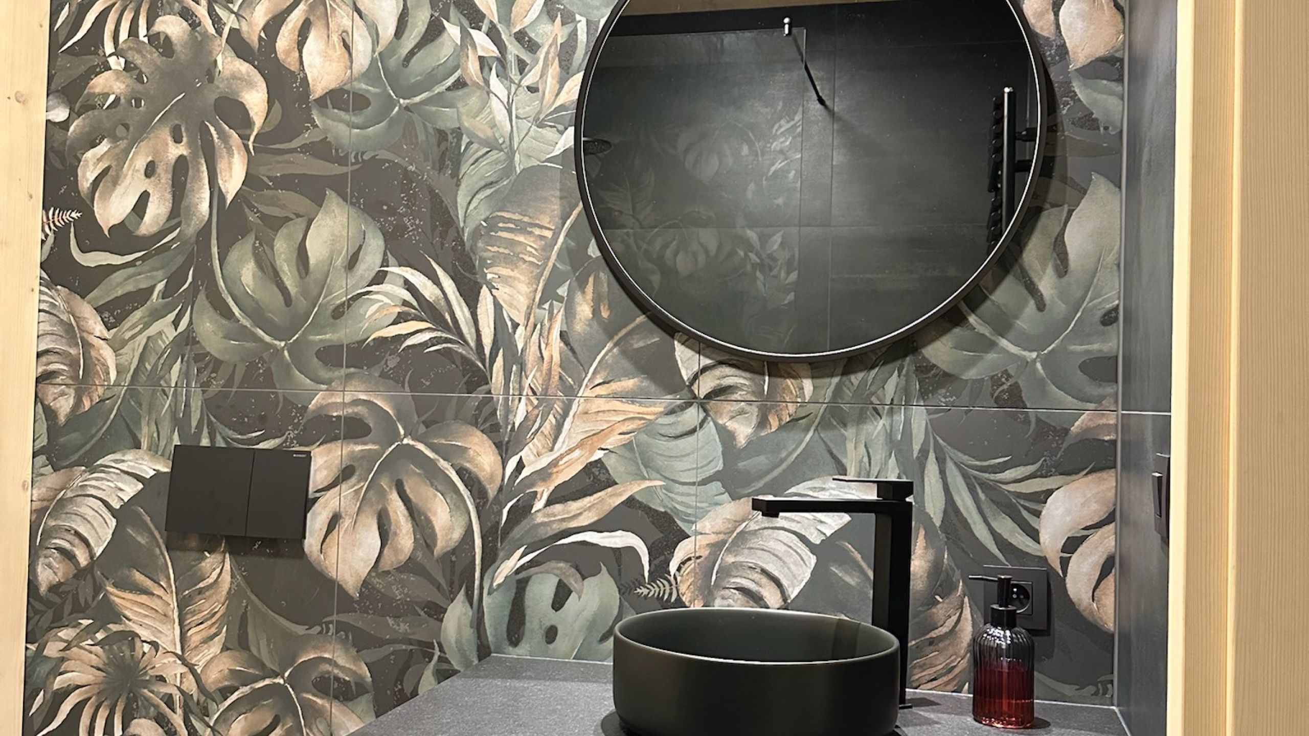 Gäste-WC mit Wandfliesen im dunklen Dschungel-Blätterdekor, rundem Spiegel und schwarzem Aufsatzbecken