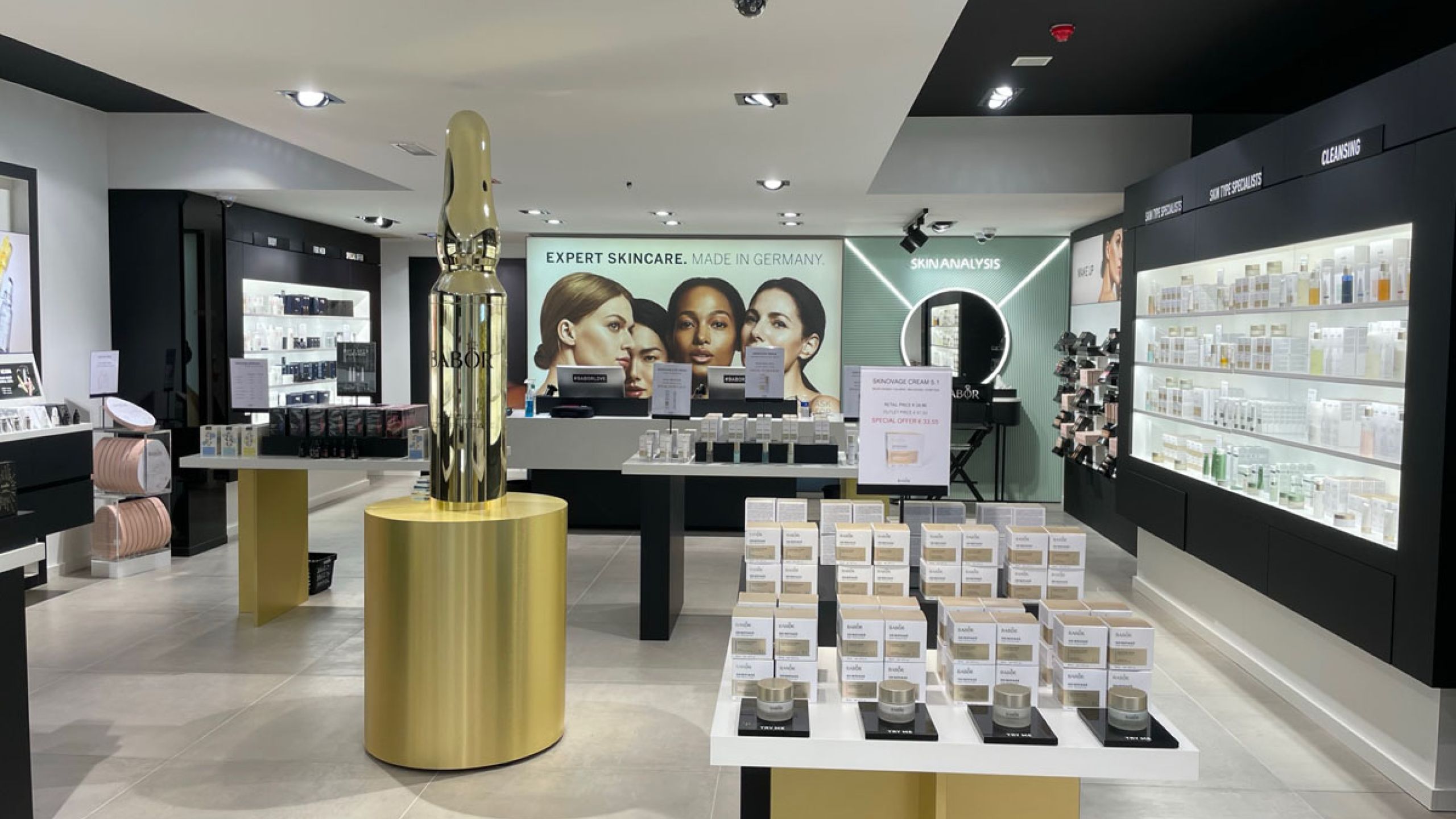 BABOR-Geschäft mit hellgrauem Großformat-Fliesenboden, Produktregalen und Wandbild „Expert Skincare. Made in Germany“