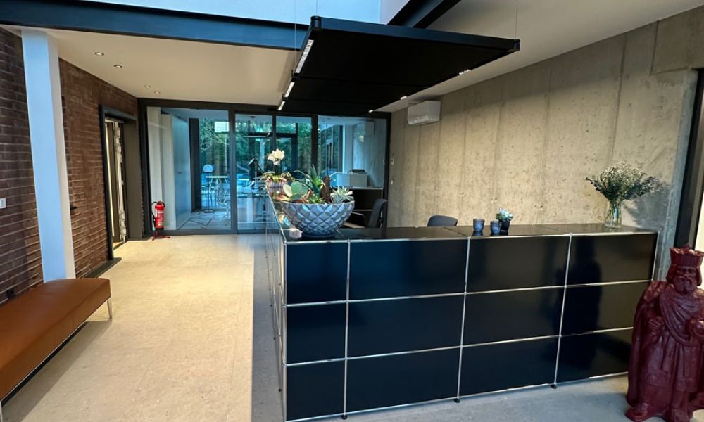 Empfangsbereich eines Bürogebäudes mit Galerie, Sichtbetonwand und hellen Großformatfliesen in Terrazzo-Optik