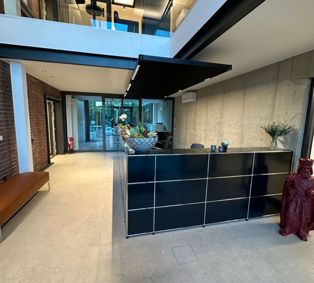 Empfangsbereich eines Bürogebäudes mit Galerie, Sichtbetonwand und hellen Großformatfliesen in Terrazzo-Optik