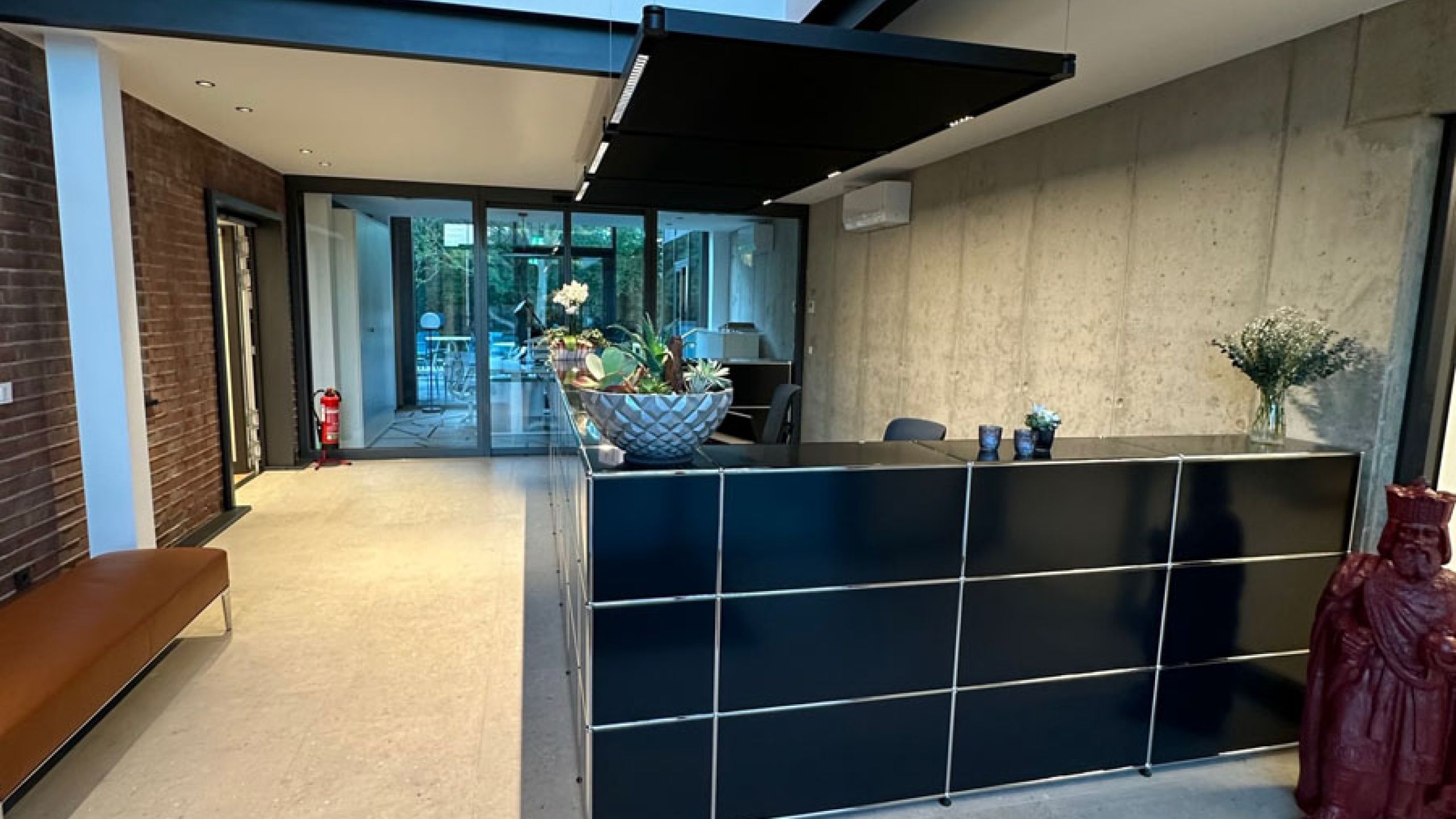 Empfangsbereich eines Bürogebäudes mit Galerie, Sichtbetonwand und hellen Großformatfliesen in Terrazzo-Optik
