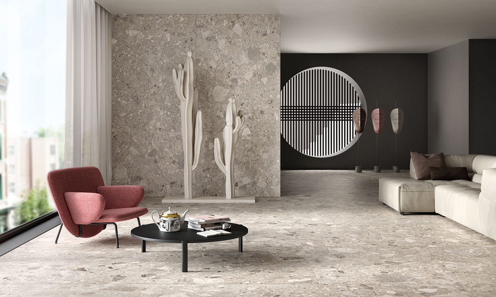 Wohnraum mit großformatigen Boden- und Wandfliesen in Terrazzo-Optik, rotem Sessel und Couchtisch