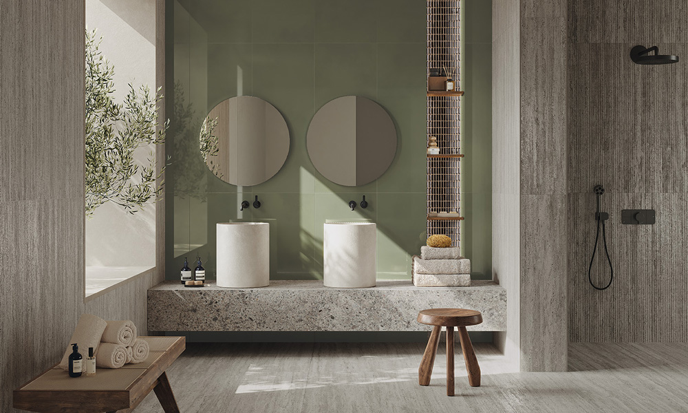Badezimmer mit grünen Wandfliesen, Travertinoptik und Waschtisch aus Steinoptik mit zwei Säulenbecken