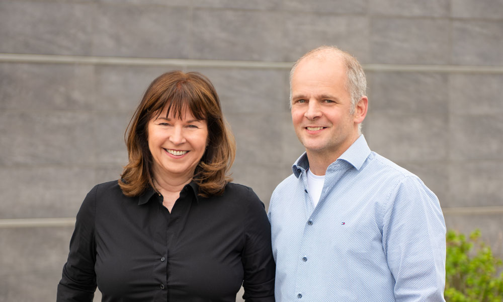 Rita Scheins und Markus Beißel vor der Fassade des Firmengebäudes in Aachen