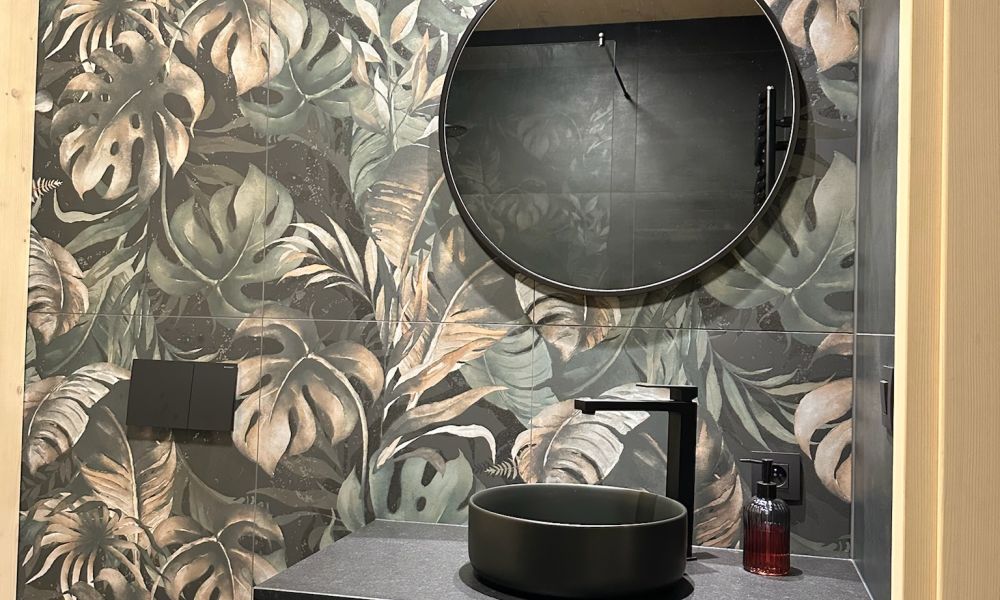 Gäste-WC mit Wandfliesen im dunklen Dschungel-Blätterdekor, rundem Spiegel und schwarzem Aufsatzbecken