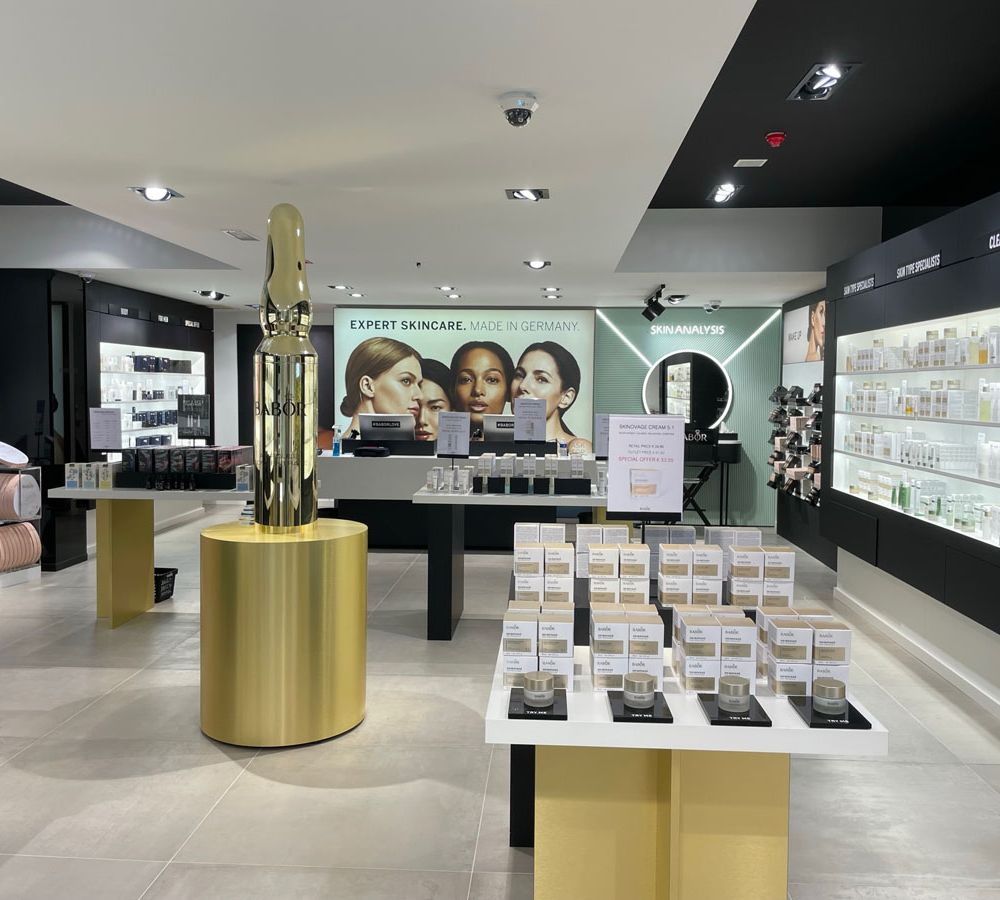 BABOR-Geschäft mit hellgrauem Großformat-Fliesenboden, Produktregalen und Wandbild „Expert Skincare. Made in Germany“